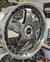 Close-up of a shiny metallic wheel rim on a blurred background
