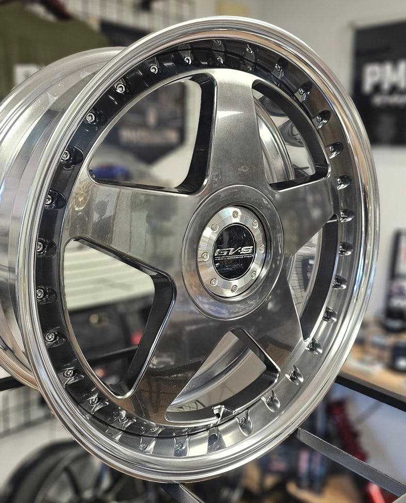 Close-up of a shiny metallic wheel rim on a blurred background