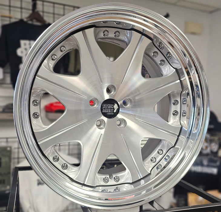Close-up of a silver alloy wheel with a visible brand logo on a blurred background.