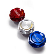 Three metal oil caps in red, silver, and blue on a white background with 'TOM'S' branding.