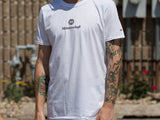 White MEISTERSCHAFT T-shirt featuring the brand logo, worn by a person with tattoos, set against an outdoor background.