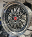 Close-up of a shiny silver car wheel rim with a red center cap on a tiled floor.