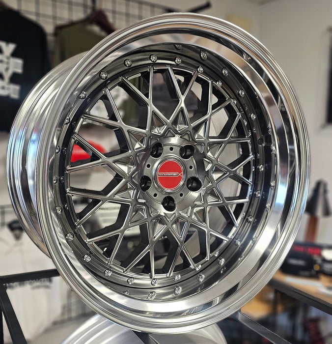 Close-up of a shiny silver car wheel rim with a red center cap on a reflective surface.